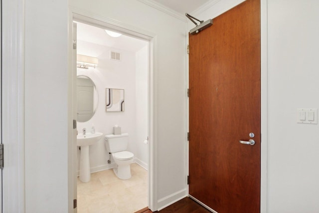 bathroom featuring baseboards, visible vents, toilet, crown molding, and a sink