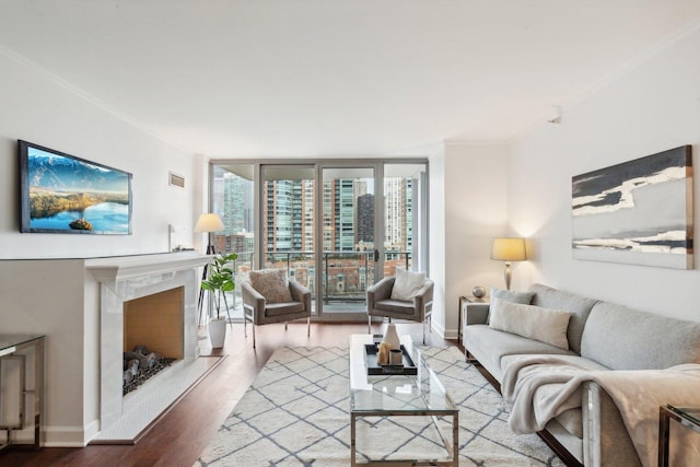 living area featuring floor to ceiling windows, ornamental molding, a high end fireplace, wood finished floors, and baseboards