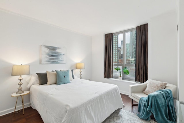 bedroom with a view of city, baseboards, and dark wood-type flooring