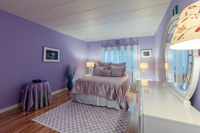 bedroom featuring multiple windows, wood finished floors, and baseboards