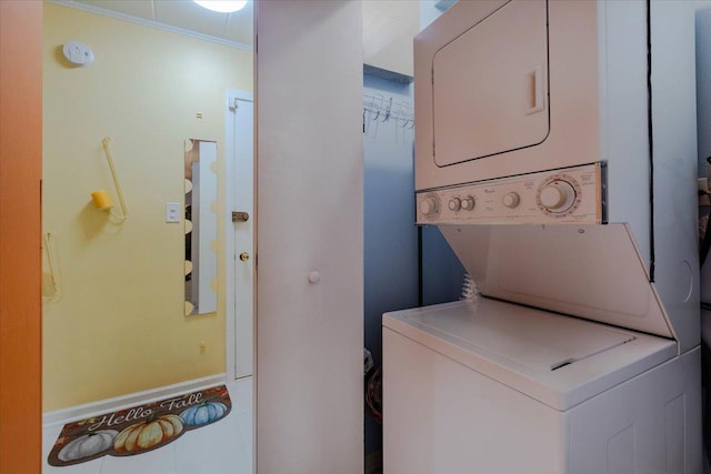 laundry room with crown molding and stacked washer / dryer