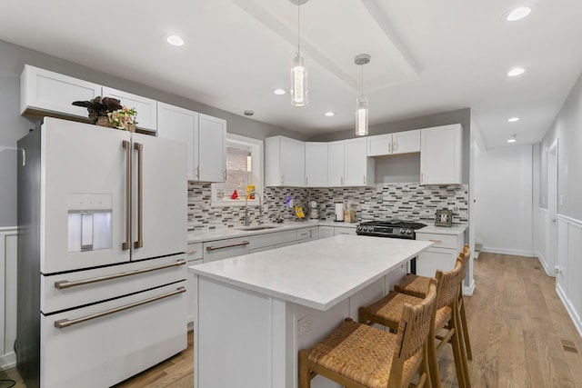 kitchen with a center island, white appliances, light countertops, and a sink