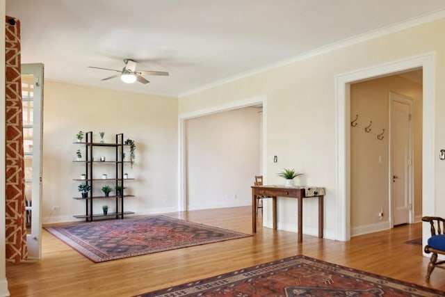 interior space with crown molding, baseboards, ceiling fan, and wood finished floors