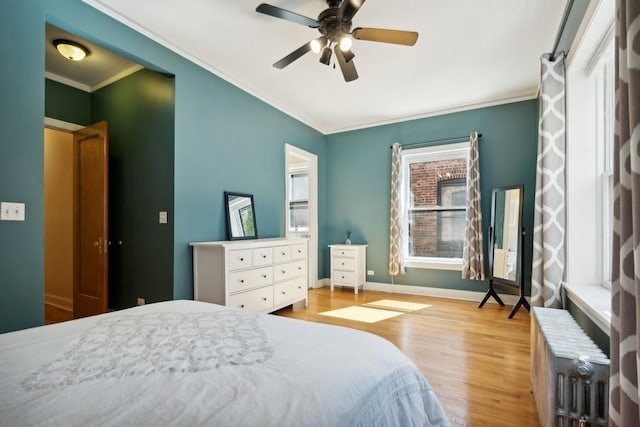 bedroom with a ceiling fan, light wood-style flooring, ornamental molding, and baseboards