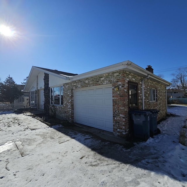 view of property exterior with an attached garage, a chimney, and brick siding