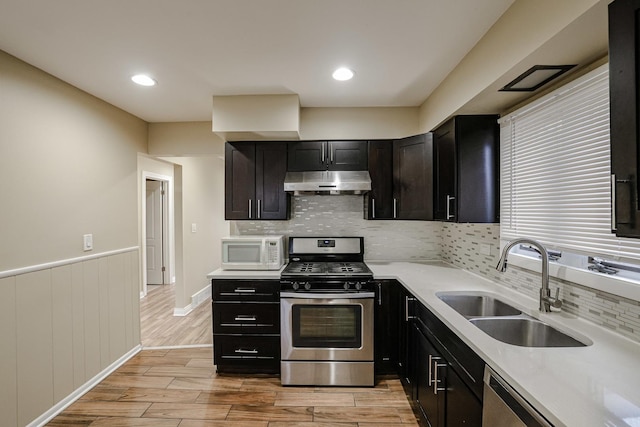 kitchen featuring appliances with stainless steel finishes, wood tiled floor, a sink, and under cabinet range hood