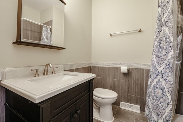 bathroom featuring toilet, vanity, visible vents, wainscoting, and tile patterned floors