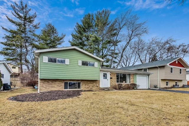 tri-level home with a garage, brick siding, and a front lawn