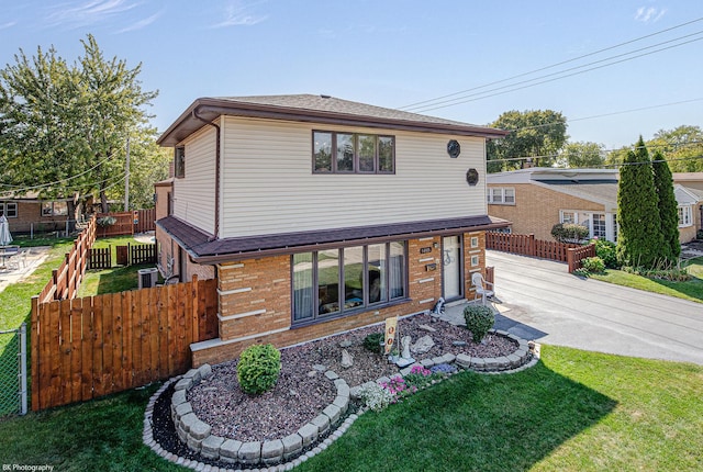 view of front of house featuring driveway, brick siding, a front lawn, and fence