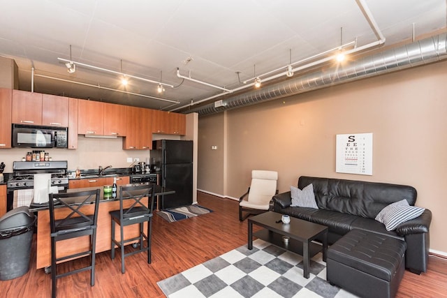 kitchen featuring dark wood finished floors, dark countertops, open floor plan, a sink, and black appliances