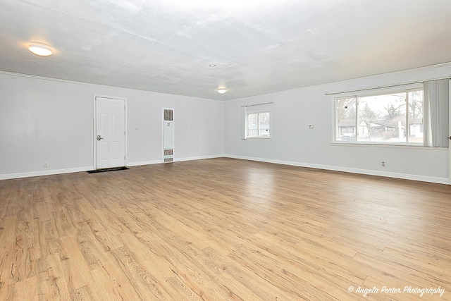 spare room with baseboards and wood finished floors