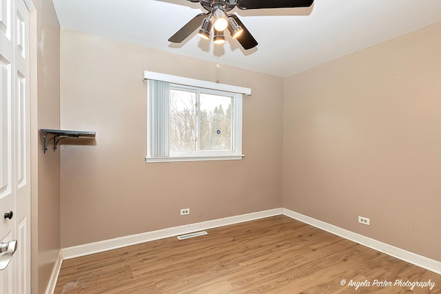 spare room with a ceiling fan, visible vents, baseboards, and wood finished floors