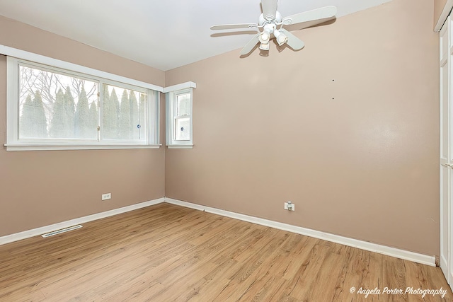 spare room with a ceiling fan, light wood-type flooring, visible vents, and baseboards