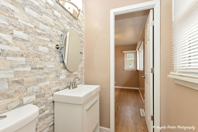 bathroom with visible vents, toilet, vanity, wood finished floors, and baseboards