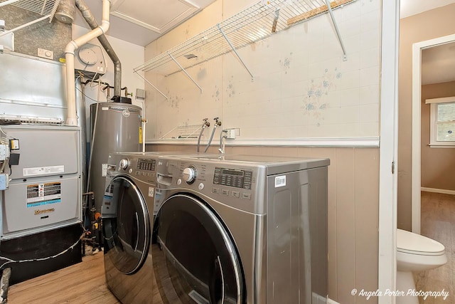 laundry room featuring water heater, laundry area, light wood finished floors, and washer and clothes dryer