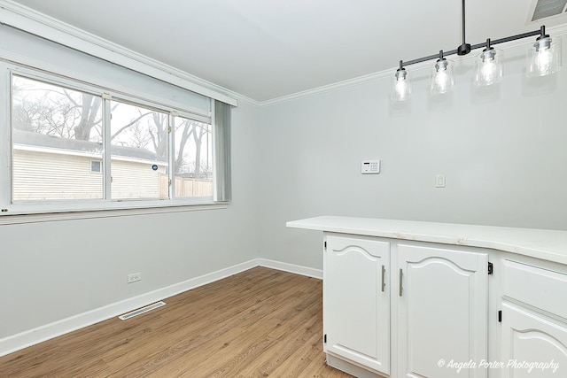 spare room with baseboards, light wood-style flooring, visible vents, and crown molding