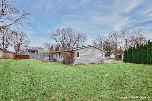 back of house featuring a yard, a chimney, and fence