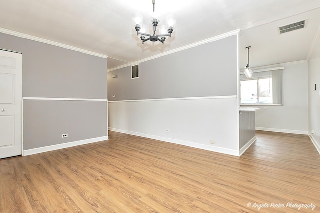 spare room featuring light wood finished floors, baseboards, visible vents, and ornamental molding