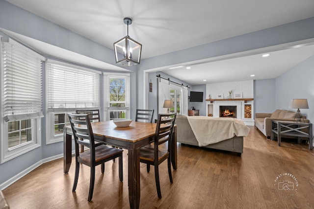 322 Arlington Ave, Naperville, IL 60565 - dining room featuring a barn door, dark wood-type flooring, a chandelier, a brick fireplace, and baseboards
