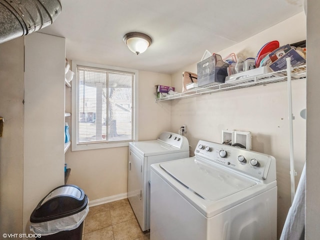 clothes washing area with laundry area, washing machine and dryer, light tile patterned floors, and baseboards