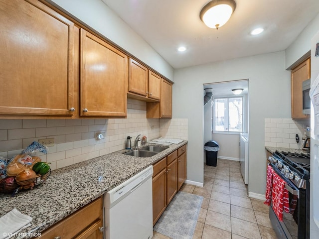 kitchen with light tile patterned flooring, white dishwasher, a sink, baseboards, and range with gas cooktop