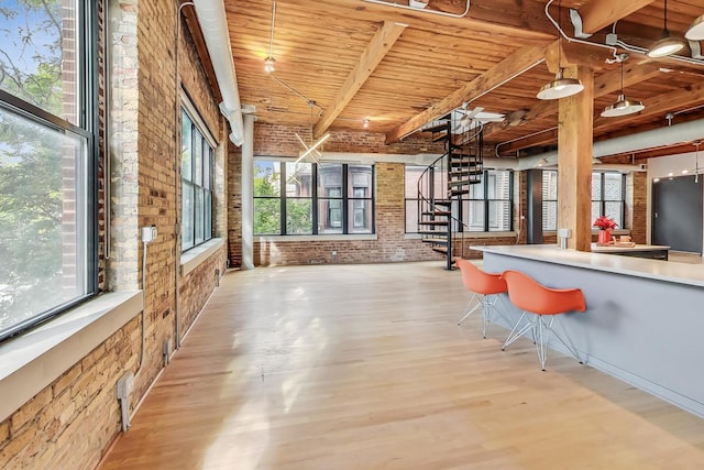 kitchen featuring wooden ceiling, brick wall, light wood-style flooring, a kitchen bar, and pendant lighting