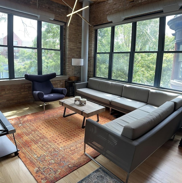 interior space featuring a towering ceiling, brick wall, and wood finished floors