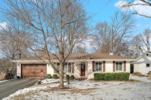 ranch-style home with aphalt driveway, an attached garage, and brick siding