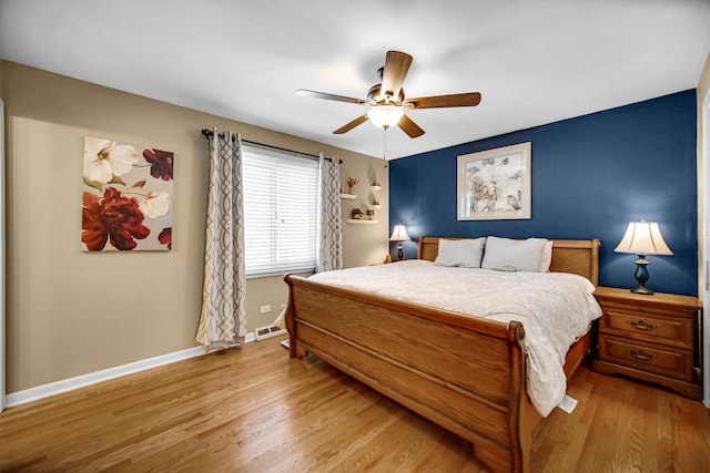 bedroom featuring light wood-type flooring, visible vents, baseboards, and ceiling fan