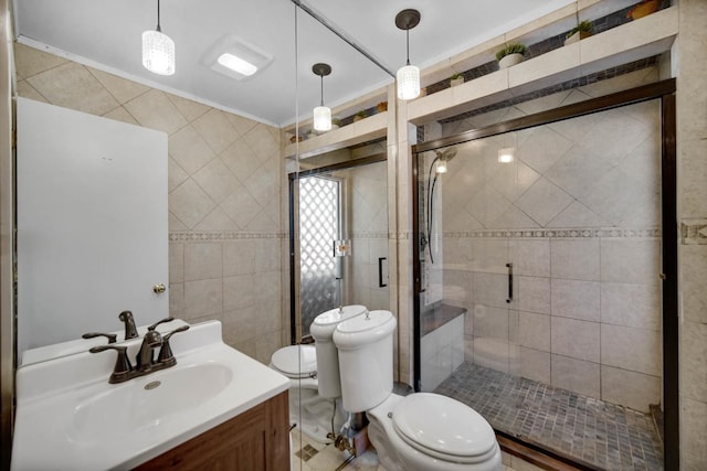 bathroom with a stall shower, toilet, crown molding, vanity, and tile walls