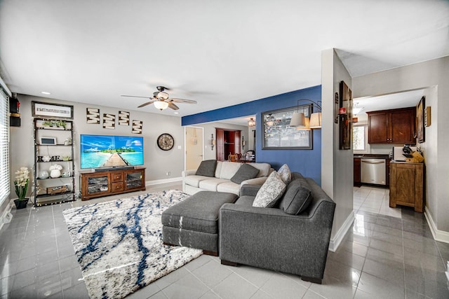 living area with light tile patterned floors, ceiling fan, and baseboards