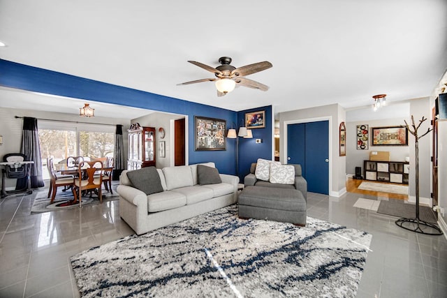 living room featuring ceiling fan, light tile patterned floors, and baseboards