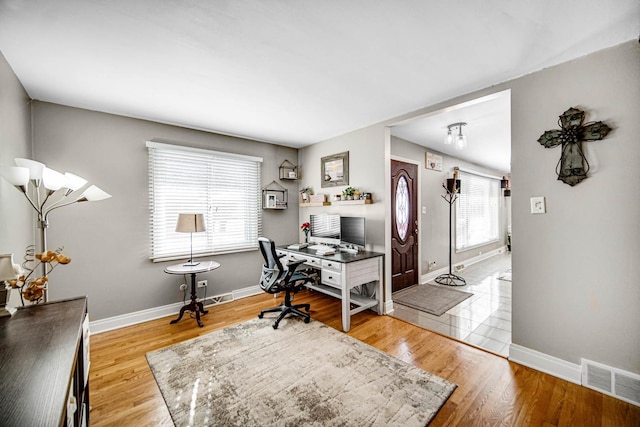 office with light wood-style flooring, visible vents, and baseboards