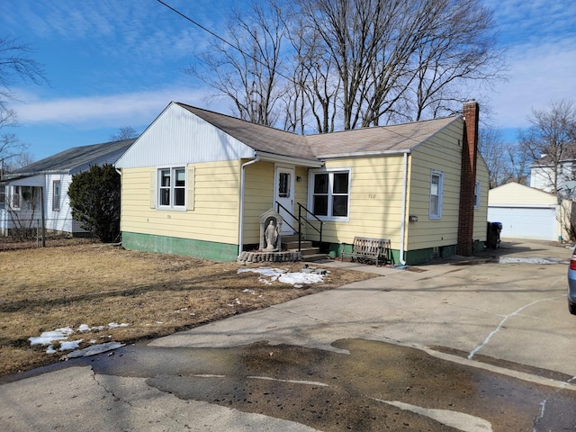 view of front of property with entry steps, a garage, a chimney, and an outbuilding