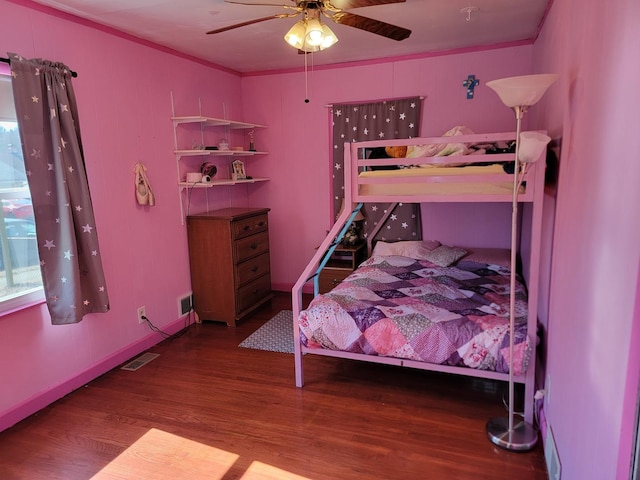 bedroom with ceiling fan, visible vents, wood finished floors, and ornamental molding