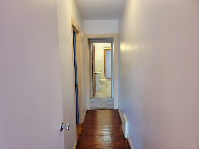 hallway featuring baseboards and dark wood-style flooring