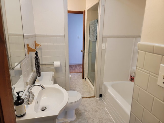 full bath with toilet, a sink, tile walls, wainscoting, and walk in shower