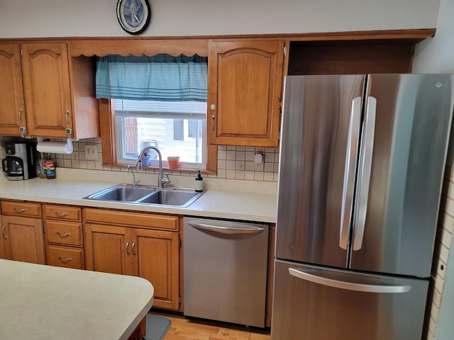 kitchen with a sink, brown cabinets, stainless steel appliances, and light countertops