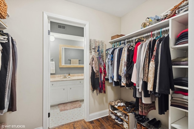 walk in closet featuring dark wood-type flooring, visible vents, and a sink