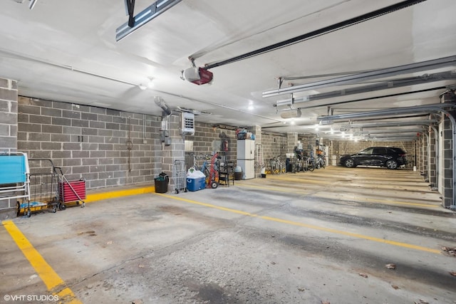 parking deck featuring concrete block wall, freestanding refrigerator, and a garage door opener