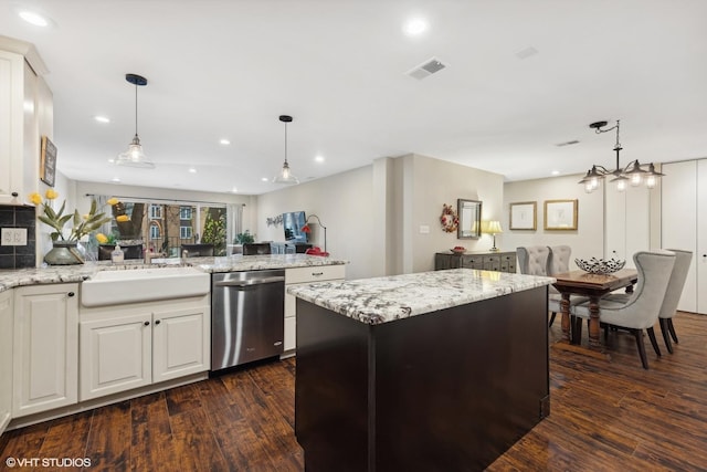 kitchen featuring dishwasher, a kitchen island, open floor plan, light stone countertops, and a sink