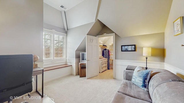 office space with wainscoting, visible vents, vaulted ceiling, and light colored carpet