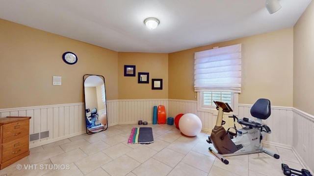 exercise area with a wainscoted wall, tile patterned flooring, and visible vents