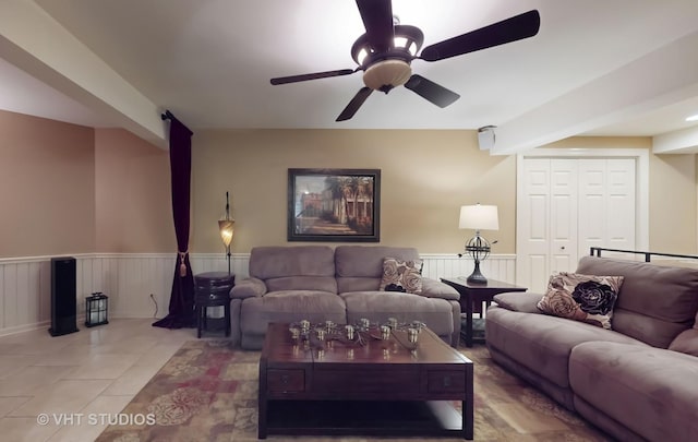 living room featuring wainscoting, tile patterned flooring, and a ceiling fan