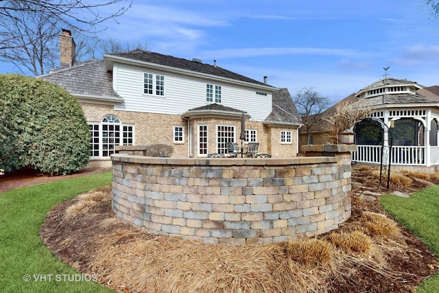 back of property featuring brick siding and a chimney