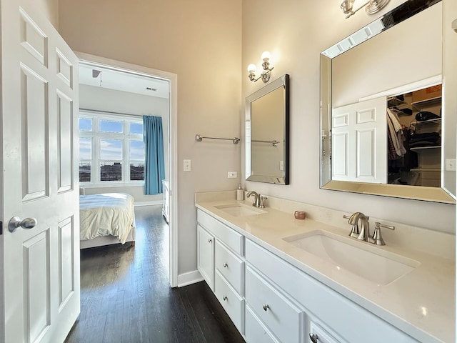 bathroom with double vanity, a sink, baseboards, and wood finished floors