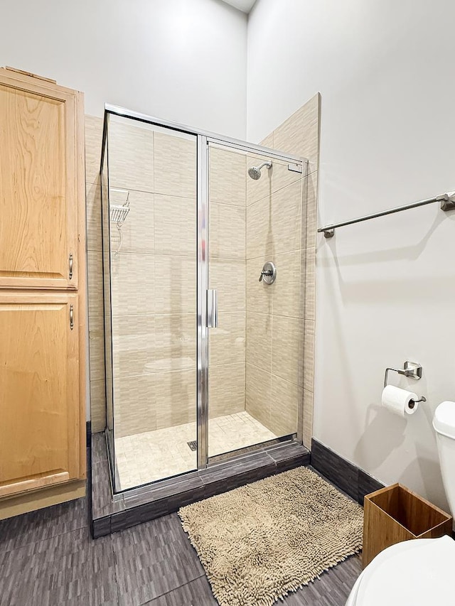 bathroom with a stall shower, toilet, and baseboards