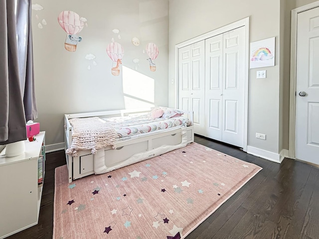 bedroom featuring a closet, dark wood-style flooring, and baseboards