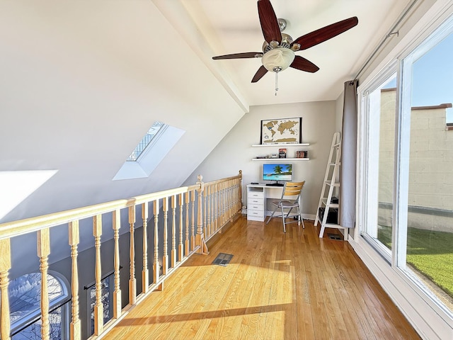 office area with hardwood / wood-style floors, lofted ceiling with skylight, and a ceiling fan