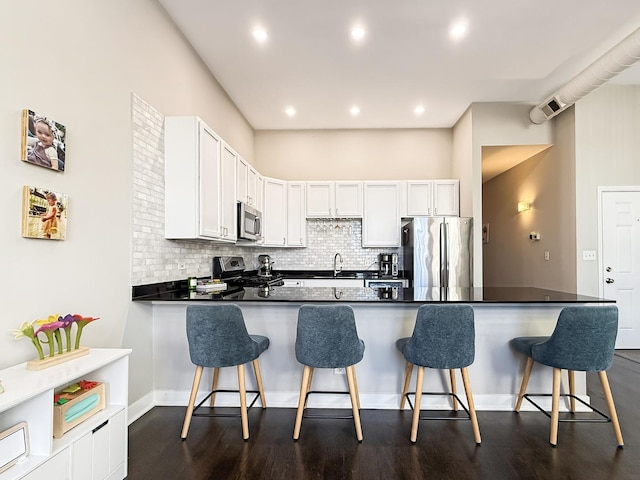 kitchen with a peninsula, tasteful backsplash, white cabinets, and stainless steel appliances